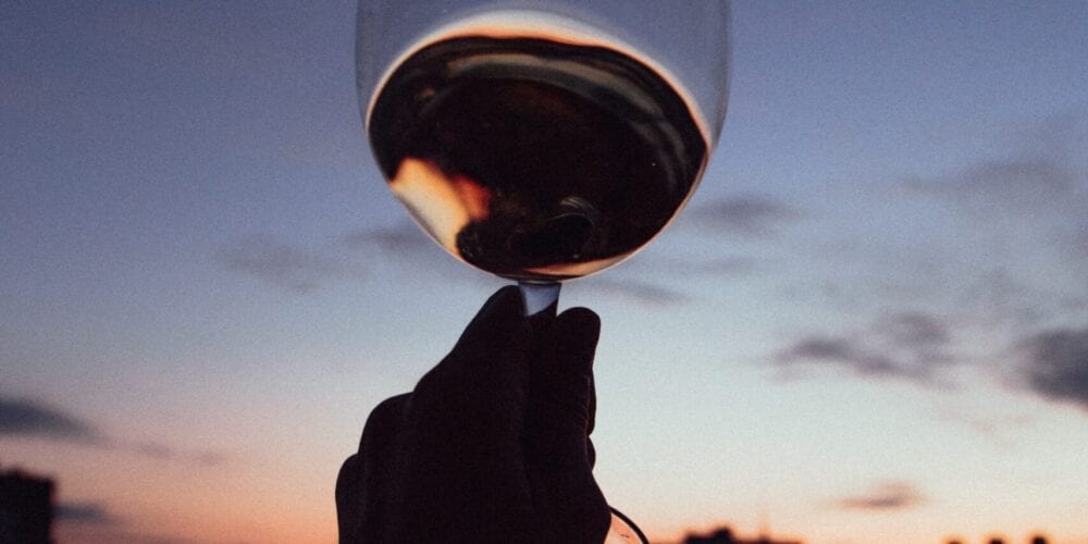 person holding clear wine glass during sunset